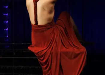 Frau posiert mit rotem Kleid auf dem Klavier