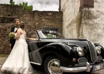 Hochzeitspaar vor dem Auto