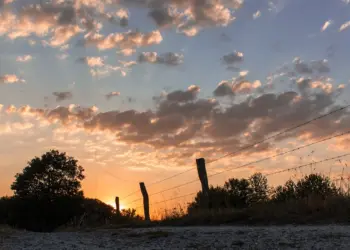 Wolkenhimmel zwischen Weidefeldern und Sonnenuntergang