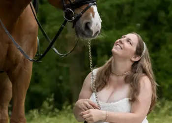 Braut und ihr Pferd posieren im Gras