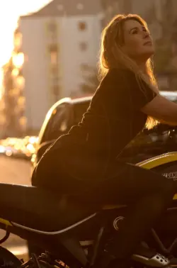 Frau auf dem Motorrad im goldenen Licht der Sonne