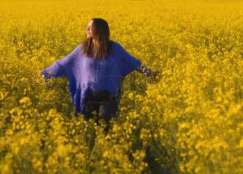 Frau im weiten lila Pulli im Rapsfeld