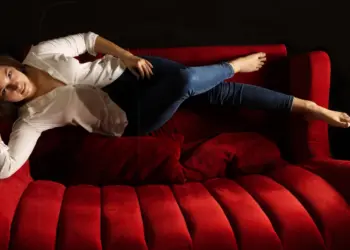 Frau liegend auf einer roten Couch im Theater