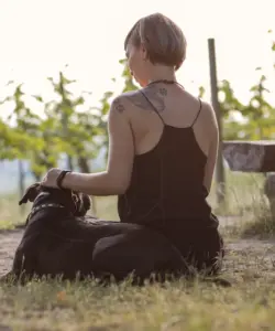 Frau mit Hund blickt in die Weinberge