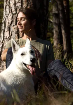Frau mit weißem Schäferhund im Wald