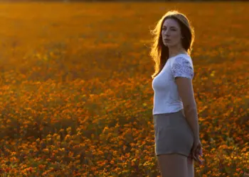 Ganzkörperaufnahme einer Frau im orangen Blumenfeld