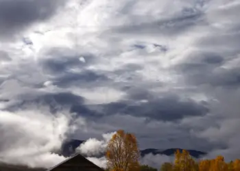 Holzhaus vor großen Wolken im Herbst
