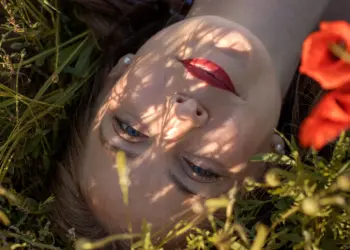 Frau liegend im Mohnfeld mit Blick in die Kamera