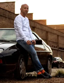 Mann posiert vor einem alten Porsche