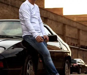 Mann posiert vor einem alten Porsche