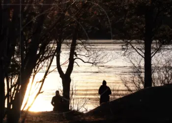 Menschen im Gegenlicht der Sonne am Fluss in Schweden