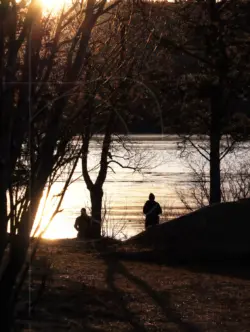 Menschen im Gegenlicht der Sonne am Fluss in Schweden