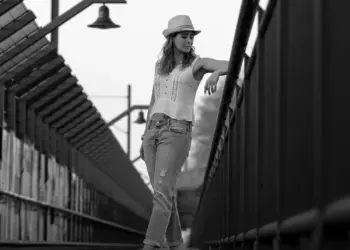 Schwarzweißportrait einer Frau stehend auf der Brücke mit Hut