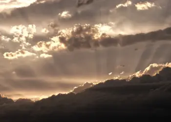 Sonnenstrahlen hinter dicken Wolken am Himmel