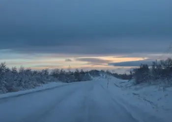 Verschneite Straße in Schweden im November im Sonnenuntergang